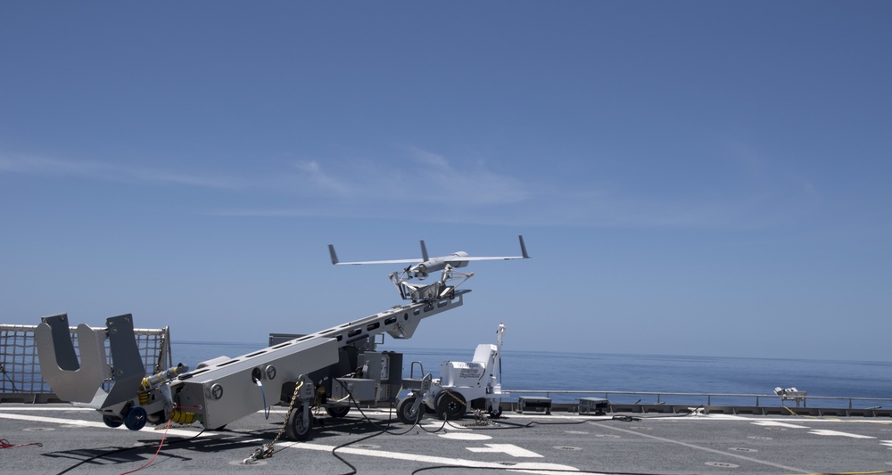 A ScanEagle drone launching from a catapult on a ship at sea.